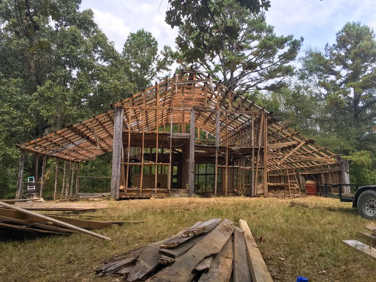 Demolition services in Tampa, FL: an old wood outbuilding stripped to its frame, with salvaged boards stacked on the grass